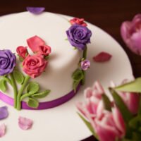 White cake with pink and purple roses